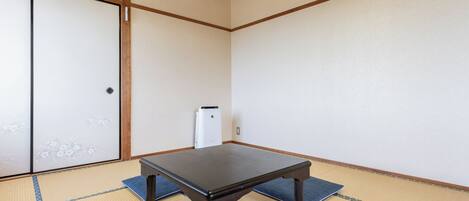 Una habitación con esteras de tatami, una mesa baja, un calentador y una puerta corredera.