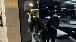 A sculpture of a horse with a lamp on its head, placed on a platform in a room with brick walls and a glass window. - Modern Studio in Chicó Norte (Bogotá, D.C.)