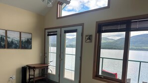 Ein Zimmer mit Bett, Schreibtisch, Stuhl, einem Fenster mit Seeblick und einer Tür zu einem Außenbereich.