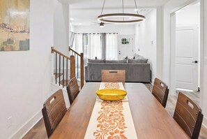 A dining area with a wooden table, chairs, a central yellow bowl, and a patterned runner. - Luxurious New Construction 4-bedroom house in charming Decatur (Decatur)