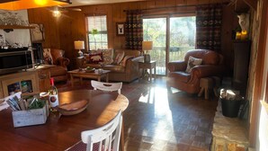A cozy living room with a wooden floor, a dining area with a table and chairs, a sofa, and a fireplace.