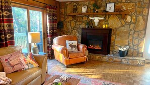 A cozy living room with a stone fireplace, leather sofa, and patterned rugs.