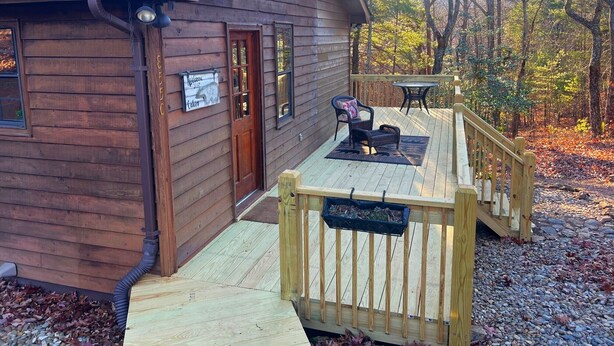 A wooden cabin with a deck, a porch, and a welcome sign.