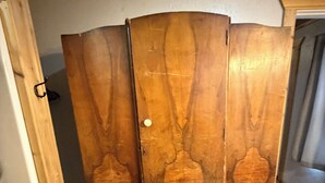 A wooden wardrobe with a curved design, a white door knob, and a visible hinge.