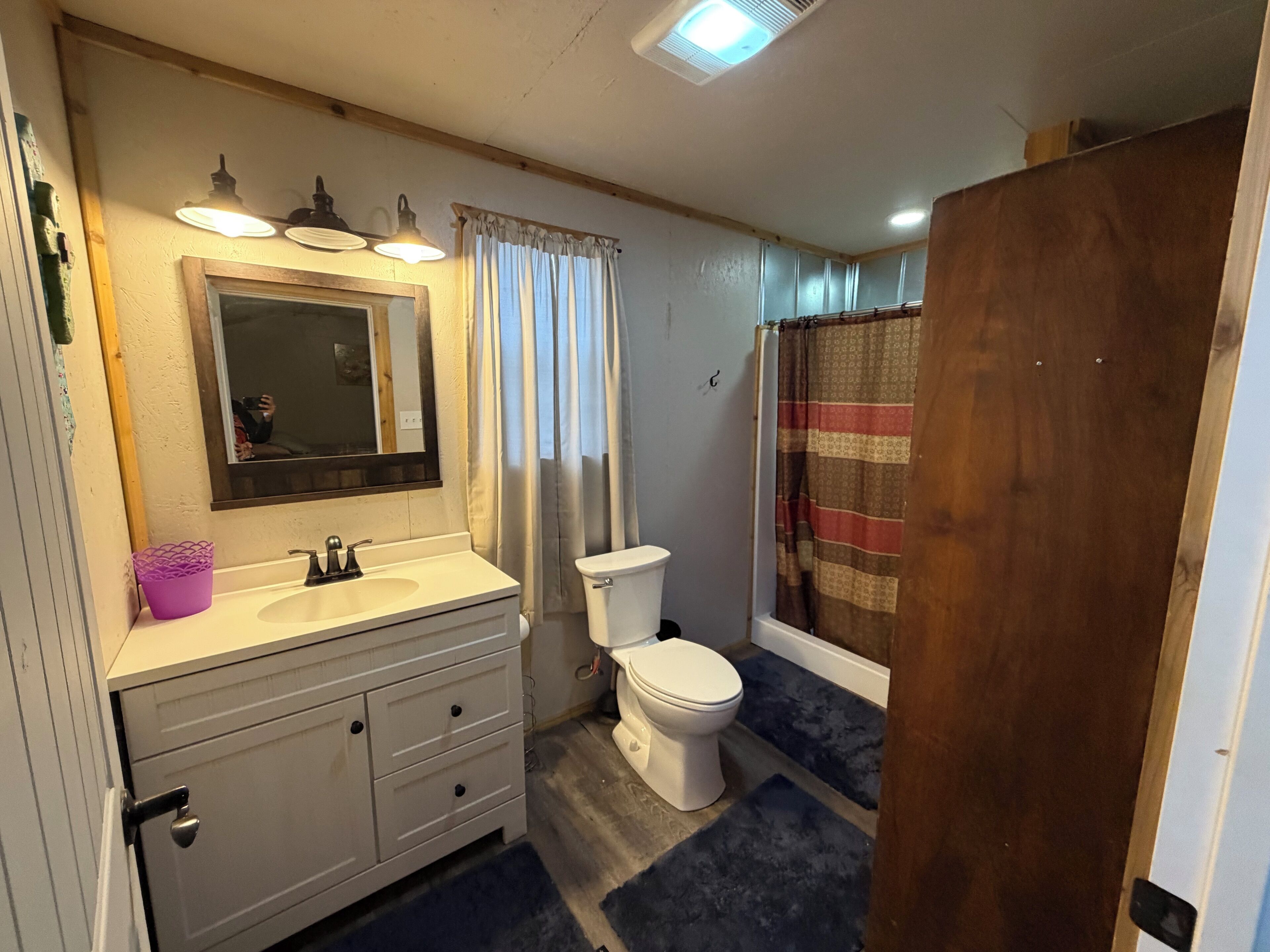 A bathroom with a sink, mirror, toilet, and shower curtain.