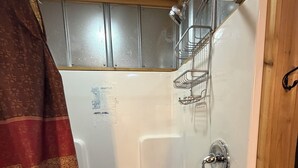 A shower with a metal rack, a showerhead, and a drain.