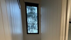 Eine enge Treppe mit Holzstufen und einem kleinen Fenster am Obergeschoss.