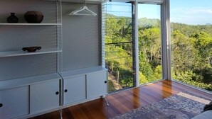 Ein Zimmer mit großem Fenster, einer weißen Regaleinheit und einer Kleiderstange.