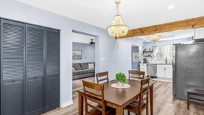 Een moderne keuken met een eethoek, houten balken in het plafond en een kroonluchter.