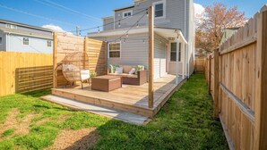 A backyard with a wooden deck, a wicker chair, and a sofa. - Church Hill Hideaway #1 | 3 BR Backyard Oasis (Richmond)