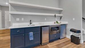 Eine moderne Küche mit weißer Arbeitsplatte, dunkelblauen Schränken, einem Edelstahl-Kühlschrank und einem Backofen.