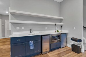 Eine moderne Küche mit weißer Arbeitsplatte, dunkelblauen Schränken, einem Edelstahl-Kühlschrank und einem Backofen.