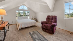Een slaapkamer met een bed, een stoel, een bureau en een raam.