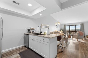Une cuisine moderne dotée d’un îlot central, d’un coin repas offrant une vue agréable et d’un balcon aménagé avec des sièges.