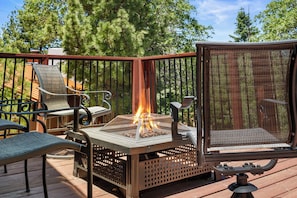 Eine Terrasse mit Feuerstelle, Gartenmöbeln und einem Moskitonetz.