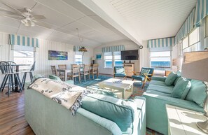 A living room with a sofa, chairs, a TV, and a view of the sea. - York - Duck, Carolina Dunes, Oceanfront, Ocean View, Hot Tub, Large Decks, Pets OK (Duck)
