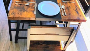Una mesa rectangular para comer con un camino de mesa negro en el centro, rodeada de sillas de madera con estructura de metal negro.