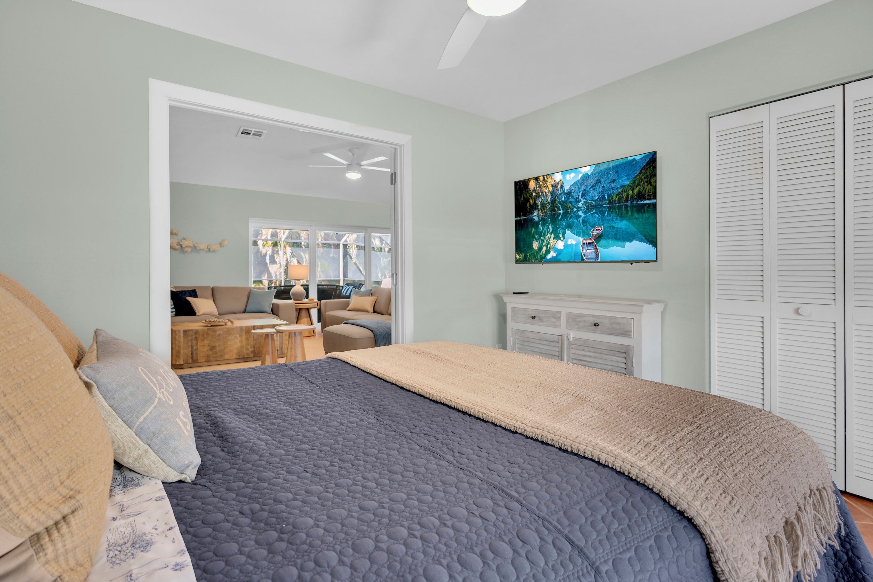 Une chambre à coucher avec un lit, un téléviseur fixé au mur et une armoire.