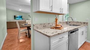 Una cucina moderna con mobili bianchi, un piano di lavoro in granito e una lavastoviglie.