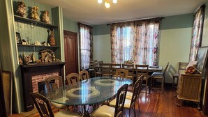A dining room with a glass table surrounded by chairs, a fireplace, and floral curtains. - Traditional Bed & Breakfast in Irvine KY with Swimming pool, Wi-Fi Room 2 (Irvine)