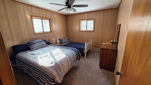 A bedroom with two beds, a ceiling fan, and two windows.