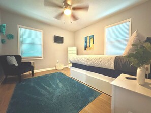 A bedroom with a bed, a ceiling fan, a dresser, a chair, and a window with blinds. - Gorgeous 3-bedroom bungalow with AC in vibrant Atlanta (Atlanta)