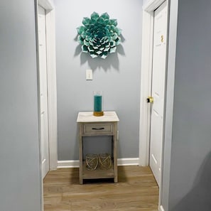A hallway with a decorative wall piece, a small table with a teal vase, and a door with a gold handle. - Gorgeous 3-bedroom bungalow with AC in vibrant Atlanta (Atlanta)