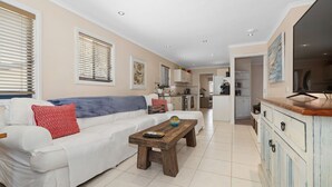 Una sala de estar con sofá, mesa de centro y cocina al fondo.