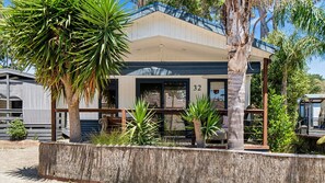 A building with a number '32' on the facade, surrounded by palm trees and other greenery. - Villa 32 at Somers Beach (somers)
