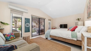 Un dormitorio con cama, televisor, sofá y balcón con vistas.