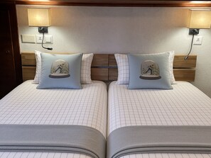 Una cama doble con cabecera, dos lámparas de noche y dos almohadas con motivos invernales.
