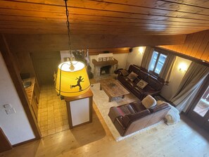 A cozy living room with a wooden ceiling, a sofa, a coffee table, and a lamp with a silhouette design. - Penthouse ski-in ski-out 30m from Medran lift 40m from W Verbier (Val de Bagnes)