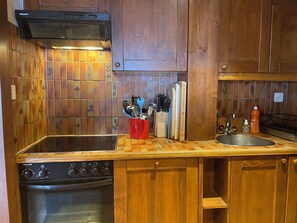A compact kitchen with wooden cabinets, a built-in oven, and a stainless steel sink. - Penthouse ski-in ski-out 30m from Medran lift 40m from W Verbier (Val de Bagnes)