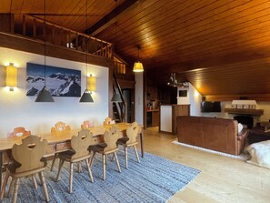 A dining area with a wooden table and chairs, a kitchen in the background, and a fireplace. - Penthouse ski-in ski-out 30m from Medran lift 40m from W Verbier (Val de Bagnes)