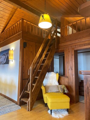 A wooden staircase with a yellow lamp above it, a yellow armchair, and a white furry rug on the floor. - Penthouse ski-in ski-out 30m from Medran lift 40m from W Verbier (Val de Bagnes)