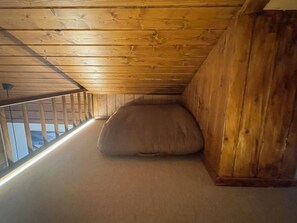Une pièce avec un plafond en pente, un banc en bois et une vue par la fenêtre.