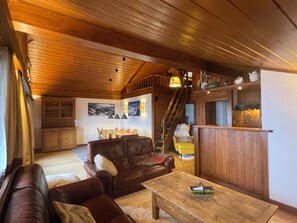 A cozy living room with a wooden ceiling, a brown leather sofa, a wooden coffee table, and a staircase leading to an upper level. - Penthouse ski-in ski-out 30m from Medran lift 40m from W Verbier (Val de Bagnes)