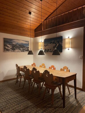A dining area with a wooden table and chairs, pendant lights, and wall-mounted lamps. - Penthouse ski-in ski-out 30m from Medran lift 40m from W Verbier (Val de Bagnes)