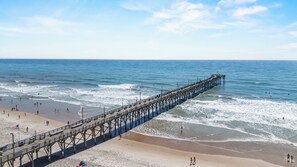 A pier extending into the ocean with people walking along it and the beach in the foreground. - Dolly's Dream 2nd Row Retreat w Ocean Views Screened Porch & Pet-Friendly living on Topsail (Surf City)
