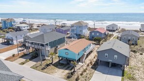 A coastal residential area with houses, a pier, and a beach in the background. - Dolly's Dream 2nd Row Retreat w Ocean Views Screened Porch & Pet-Friendly living on Topsail (Surf City)