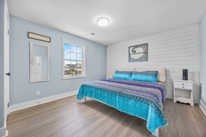 Quarto com cama, mesa de cabeceira, janela e quadro na parede.