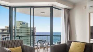 Un balcón con vista al mar, dos sillas y un sofá con un cojín.