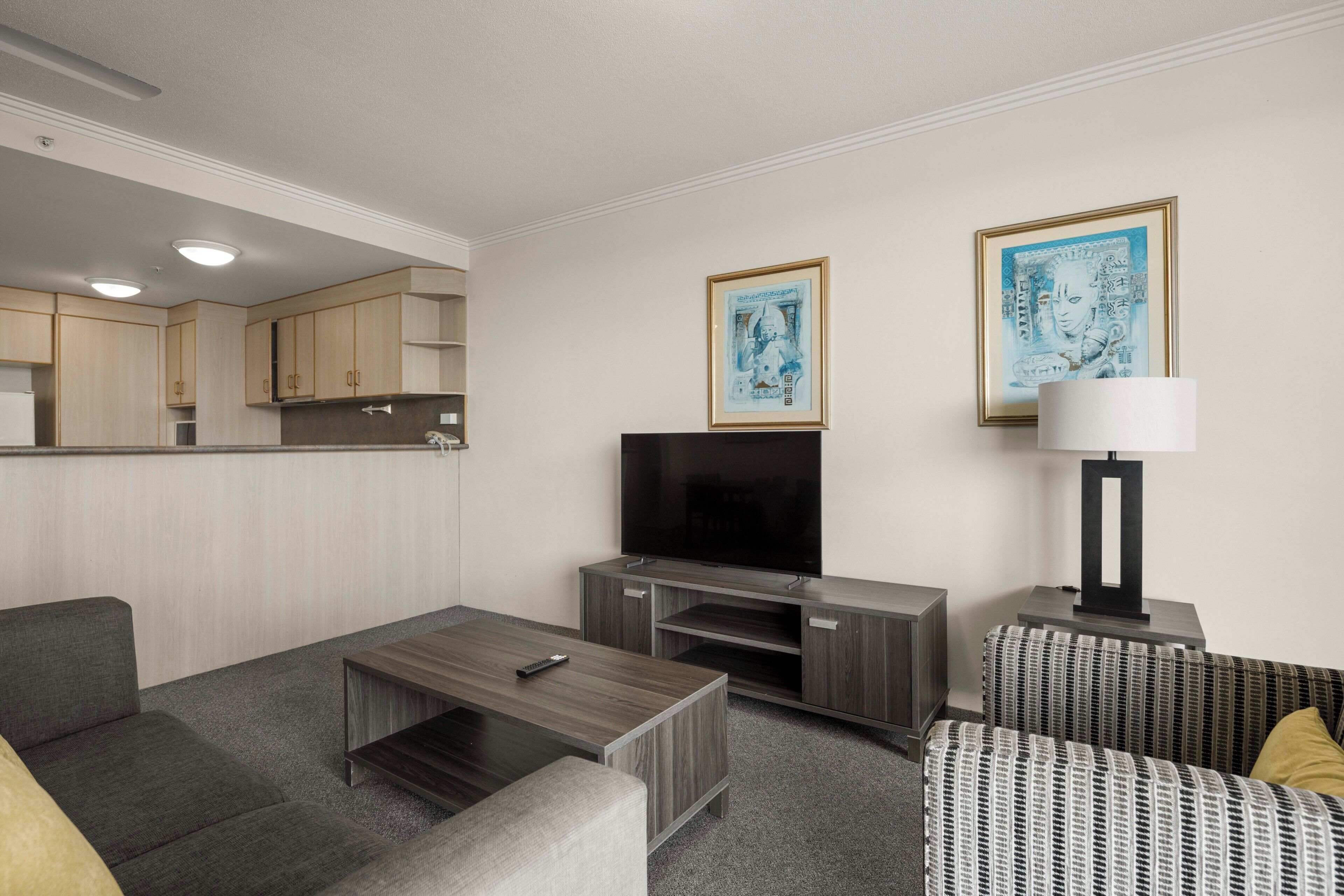 Een moderne woonkamer met een flatscreen televisie, een bank, een bijzettafeltje en een lamp.