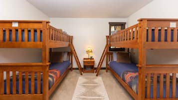 Una habitación con literas, una pequeña mesa con lámpara y una alfombra en el suelo.