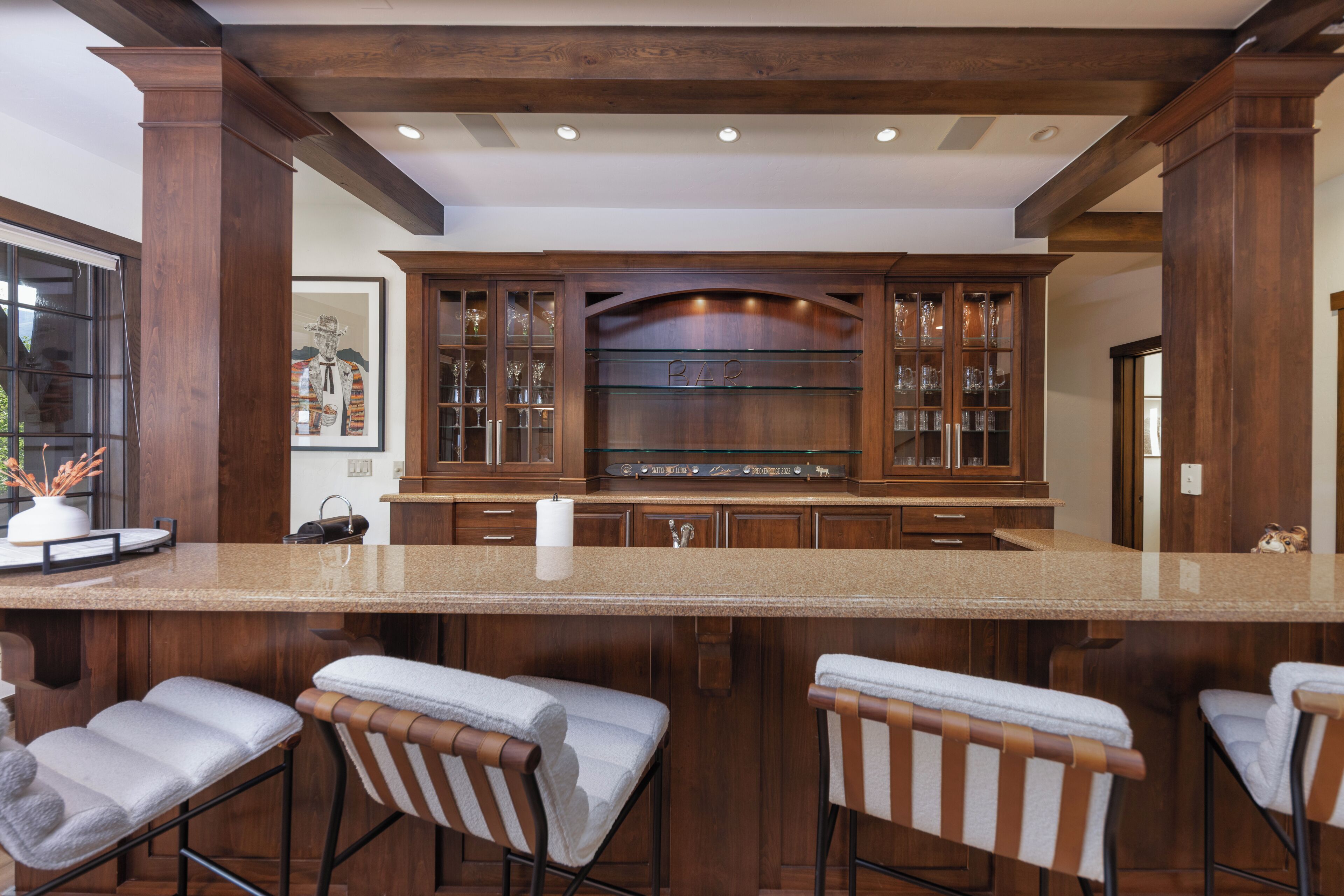 Una cocina con armarios de madera, una isla central con taburetes de bar y una obra de arte enmarcada en la pared.