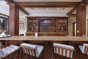 Una cocina con armarios de madera, una isla central con taburetes de bar y una obra de arte enmarcada en la pared.