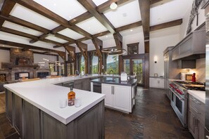 A spacious kitchen with a large island, built-in appliances, and a stone fireplace. - Unmatched Elegance, Pool Table, Hot Tub, Ski Shuttle, Fire PIt with Views!! (Breckenridge)