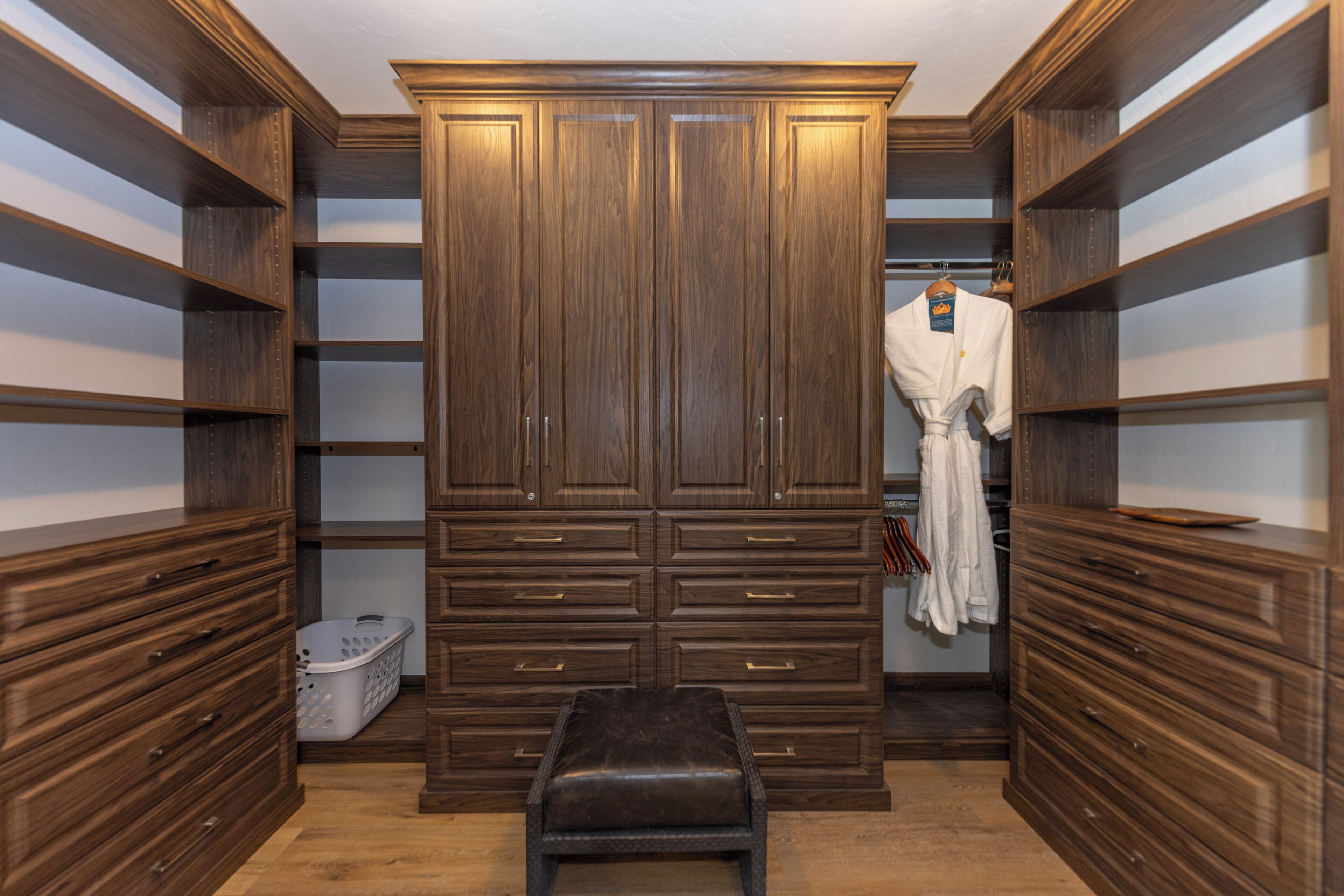 Un armario vestidor con estanterías, cajones y un banco.