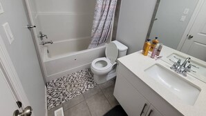 A bathroom with a bathtub, toilet, sink, and shower curtain.