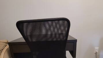 A black office chair with a mesh backrest and wheels, positioned in front of a desk.
